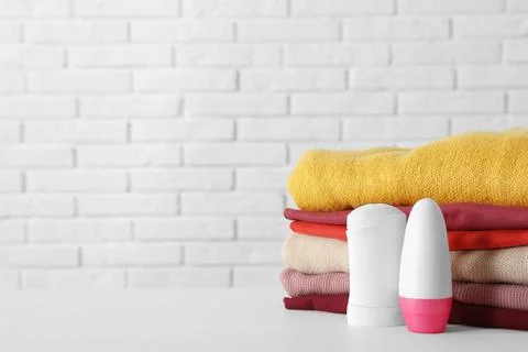 Deodorants near stack of clean clothes on white table. Space for text 스톡 사진