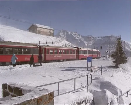 Departing train at snow covered mountain Alp Grum + blowing snow Stock Footage 45573446