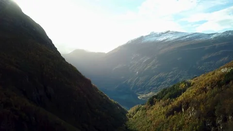 Departure from behind the mountain opens a view of the Geiranger fjord in Norway Stock Footage 82999991