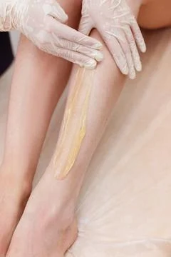 Depilation master applies sugaring paste to the legs Stock-Fotos