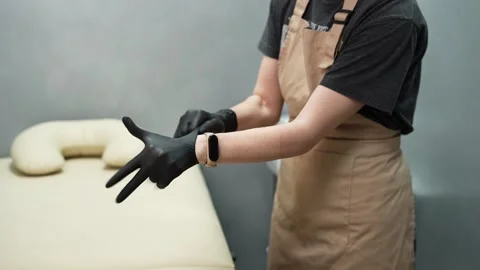 Depilation master puts on black protective gloves before the procedure Video stock 264856897