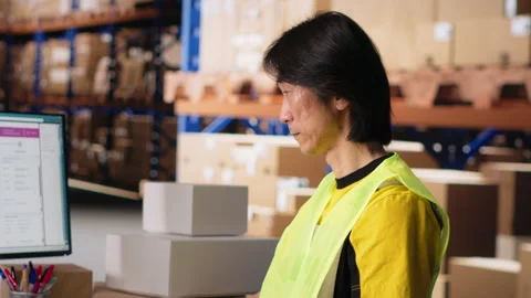 Depot asian worker processing online shopping orders on computer Stock Footage 312835992