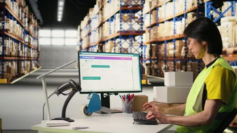 Depot asian worker processing online shopping orders on computer Stock Footage 313089030