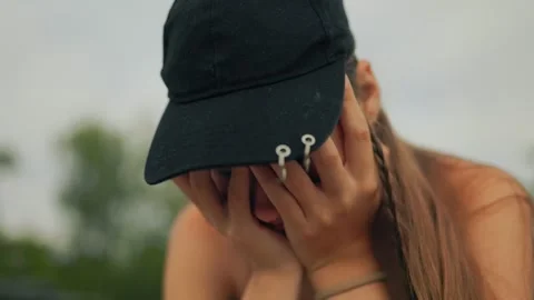 Depressed adolescent covering face with hands crying outdoors in daylight. 스톡 동영상 339810246