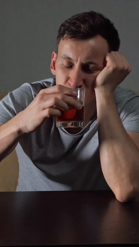 Depressed and lonely man drinking alcohol alone at home feeling sad, showing Stock Footage 342912082