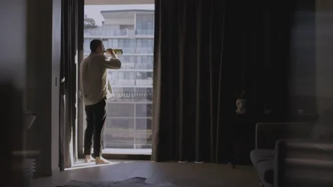 Depressed and sad man drinks alcohol by himself looking outside Stock Footage 158345348