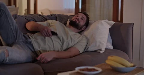 Depressed bearded man changing TV channels on sofa in apartment Stock Footage 271160480