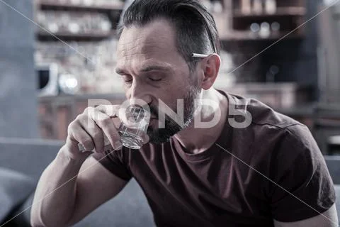Depressed bearded man drinking vodka Stock Photos
