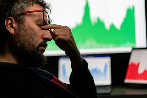Depressed businessman in front of computer with graph of unsuccessful business Stock-Fotos
