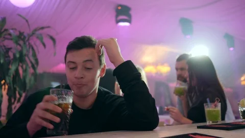Depressed drunk guy drinks chilled alcohol behind the bar stand at club on Stock Footage