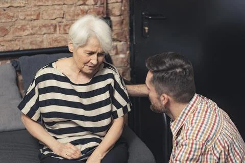 Depressed elderly caucasian grandmother suffering from dementia sitting on a Stock Photos