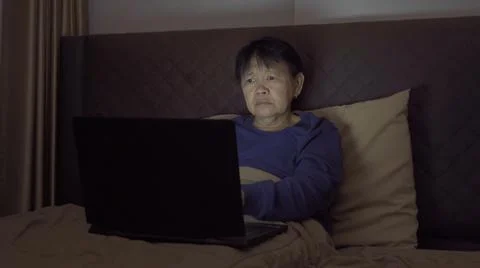 Depressed elderly old Asian woman, people using a notebook laptop computer on Stock Photos