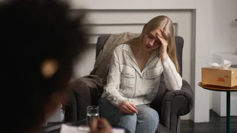 Depressed female client is talking to psychoanalyst and sitting in chair in Stock Footage 185403411
