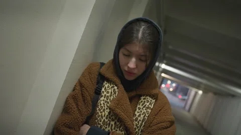 Depressed Girl Leaning Against Underpass Wall in a Brown Coat Stock Footage 283166330