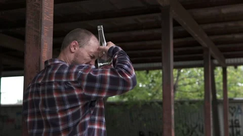 Depressed guy drinks alcohol in the gateway. Feeling lonely and hungover. Stock-Footage 251636331