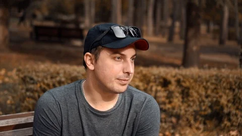 Depressed guy sitting alone in the park after divorce Stock Footage 118211313