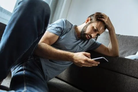 Depressed handsome man using his smartphone Foto stock