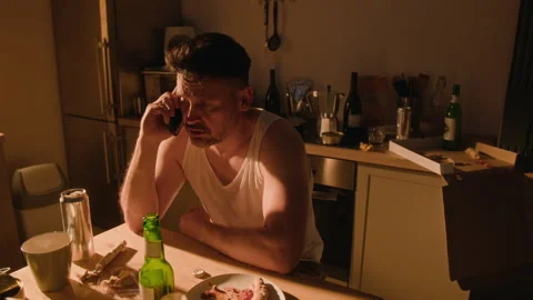 Depressed Man Drinking Alcohol from Bottle after Phone Call Stock Footage 344875748