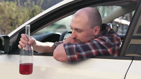 A depressed man drinks alcohol while driving a car. Stock Footage 250530234