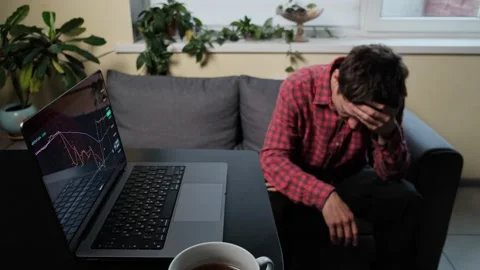 Depressed man with head down sitting on sofa in despair in home office next to Video stock 318650958