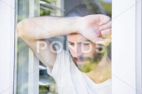 Depressed Man Leaning His Head On Window Glass