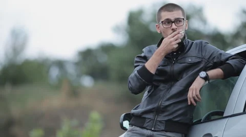Depressed man in a leather jacket smoking near the machine Stock Footage 55334158