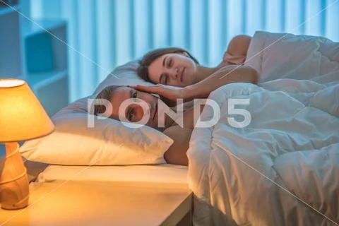 The depressed man lie with woman on the bed. Evening night time Stock Photos
