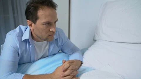 Depressed man looking at empty hospital bed, trying to cope with his grief, loss Video stock 119294877