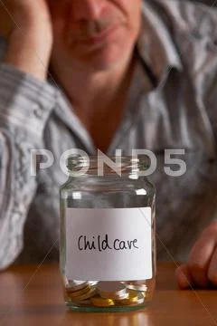 Depressed Man Looking At Empty Jar Labelled Childcare Stock Photos