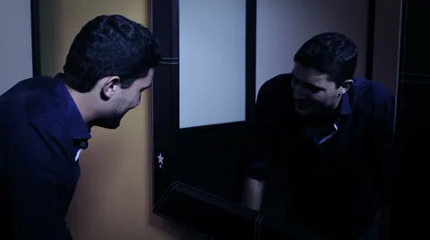 Depressed man looking in the mirror at his angry reflection Stock Footage 34272106