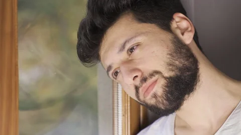 Depressed man looking out the window thoughtfully. Video stock 222504430