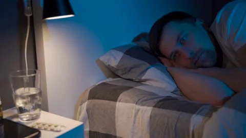 Depressed man lying in bed cannot sleep from insomnia. Young male trying to Stockbeeldmateriaal 145439822