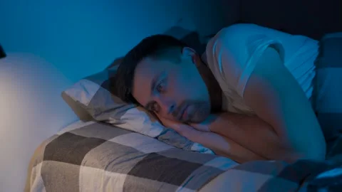 Depressed man lying in bed cannot sleep from insomnia. Young male trying to Stock Footage 145440048
