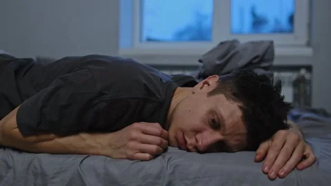 Depressed man lying in bed. Young male is trying to sleep. Restless worried guy, Stock-Footage 296055418