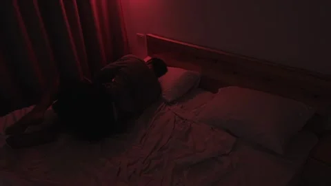 Depressed man lying on his bed staring at the ceiling before turning away and Видео 347299050