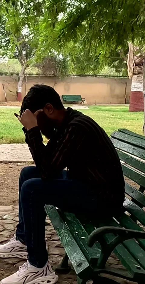 Depressed man sitting on bench in the garden Stock Footage 343267201
