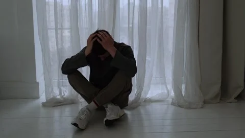Depressed man sitting on the floor with head in hands, struggling with Stock Footage 304654655