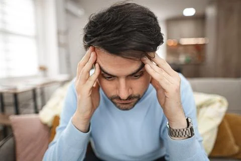 Depressed man sitting thoughtfully on couch Stock Photos
