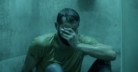 Depressed man sitting under shower in bathroom at home Stock Footage 271159554