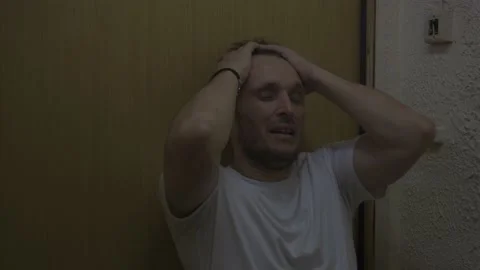 Depressed man slides down the door Stock Footage 156742194