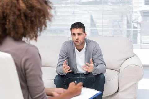 Depressed man speaking to a therapist Stock Photos
