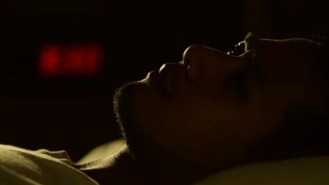 Depressed man suffering from insomnia lying in bed at night . Video stock 125172046