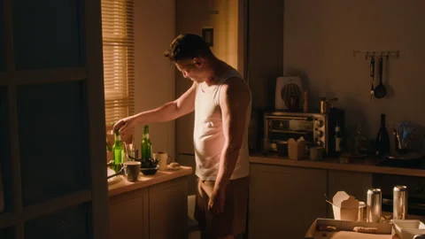 Depressed Man Sweeping Empty Cans off Table Suffering from Alcohol Abuse Stock Footage 344874183