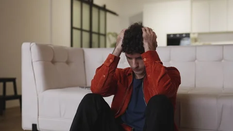 Depressed man thinking about relationship problems while sitting on the floor Stock Footage 337908289