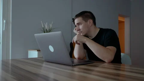 Depressed man tries hard to continue work on laptop at home Stock Footage 228859268