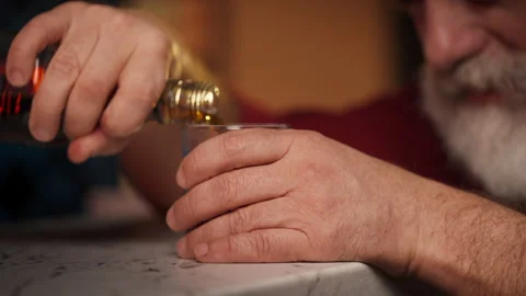 Depressed middle-aged man pours whiskey into glass, drinking alone at home Stock Footage 346714113