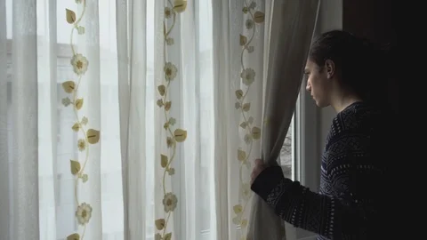 Depressed millennial guy watching the empty streets from his window Stock Footage 127330480