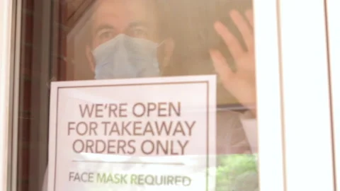 Depressed owner looking out from inside his closed restaurant during coronavirus Stock Footage 137181953
