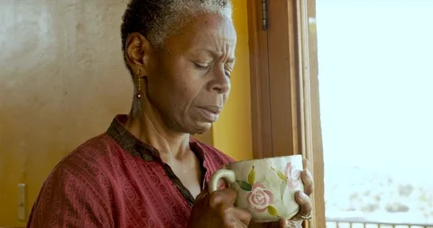 Depressed, sad, African American senior woman holding a cup of coffee Stock Footage