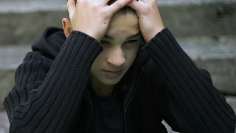 Depressed schoolboy hiding face under hoodie, victim of bulling, homelessness Stock Footage 99657319